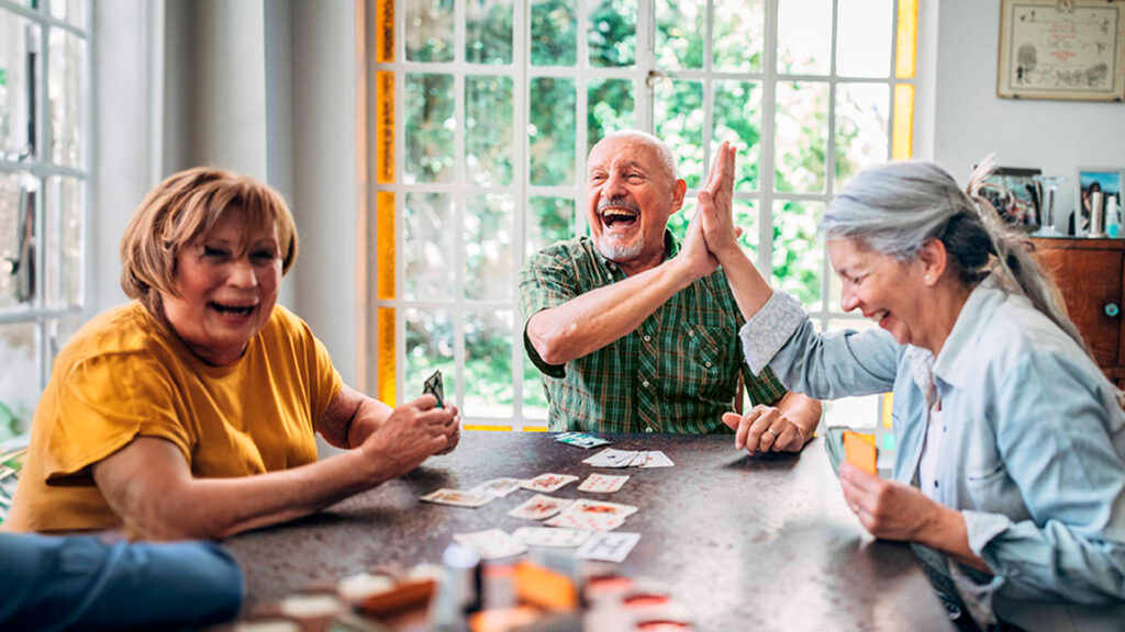 3 older people enjoying paying cards